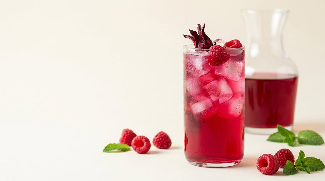 Frambozen-hibiscus ijsthee in een glas met ijs en verse frambozen