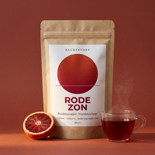Rode Zon losse thee in kraft doypack op terracotta achtergrond met halve bloedsinaasappel en een glas gezette thee
